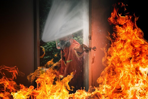 Fire in a company without commercial fire protection. On the image is a firefighter opening a door